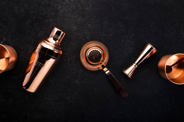 istock Copper bar tools and accessories for making cocktail. Shaker, jigger, strainer, spoon, tongs, muddler. Alcohol drink and beverages preparation concept. Black background, top view, copy space 1222829727