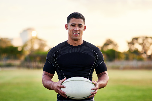 Cropped portrait of a handsome young sportsman standing alone and holding a rugby ball before an early morning practice