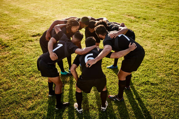 This match is ours Full length shot of a diverse group of sportsmen huddled together before playing rugby during the day sports team stock pictures, royalty-free photos & images
