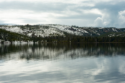This is a close up color photograph of a lake in Yellowstone national park on a cold overcast spring day.