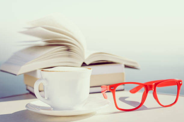 Open book and sunglasses on a meadow with clover on a sunny day, holiday relaxation in the nature during coronavirus pandemic, blurry background with copy space, selected focus, narrow depth of field
