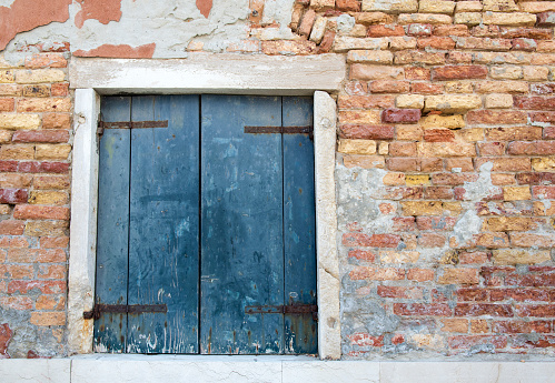 Weathered brick wall with window in Murano, a series of islands linked by bridges in the Venetian  lagoon in northern Italy, famous for its glass-making industry.