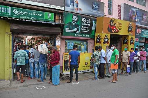 Burdwan Town, Purba Bardhaman District, West Bengal / India - May 04, 2020: Long queues of buyers as liquor shop reopen in areas outside the containment zone after the announcement of government directives during the lockdown period due to Novel Coronavirus (COVID-19) outbreak.