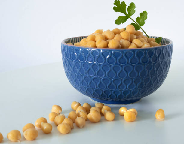 Chickpeas with coriander leaves in a blue bowl on white background