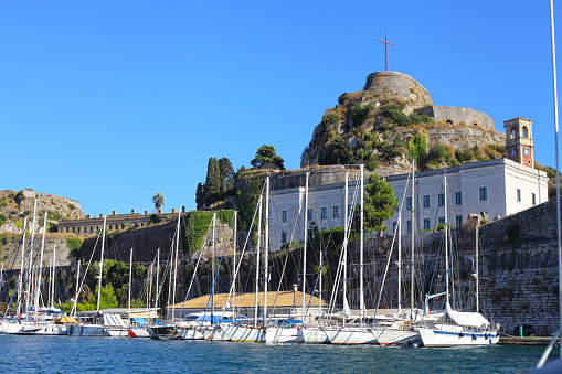 Corfu, Greece - September 04, 2017: Sail into Corfu town old harbor with lot of sailboats and crisscross on top of Old Fortress, which lies between the Gulf of Kerkyra to the North and Garitsa Bay to the south, Corfu island, Ionian Sea coast, Greece