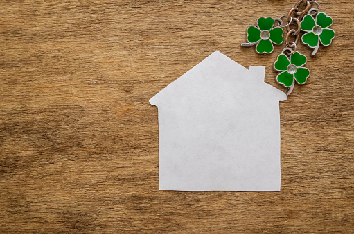 Lucky home symbol with four-leaf clover on wooden background. Copy space. St.Patrick's day holiday symbol.