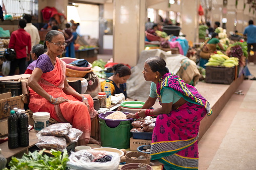 Mapusa, India - February 6th, 2020: Two unidentified Indian women talk in a farmer market of Mapusa, Goa, India. Indian markets is a place where local people traditionally learn and share latest news.