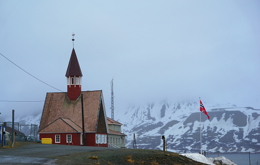 A church building and tomb grave with grass in Reine City, Lofoten islands, Nordland county, Norway, Europe. White snowy mountain hills, nature landscape background in winter season. Temple