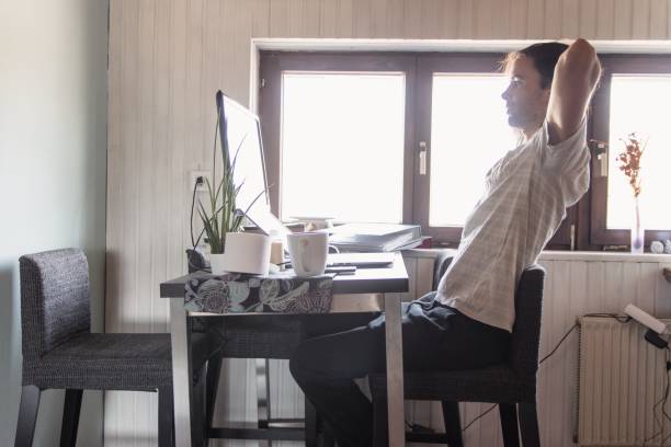 istock Man working from home stretching behind laptop 1222846243