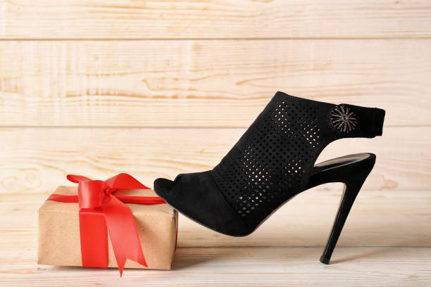 istock female shoe and gift on a white wooden background 1222847555