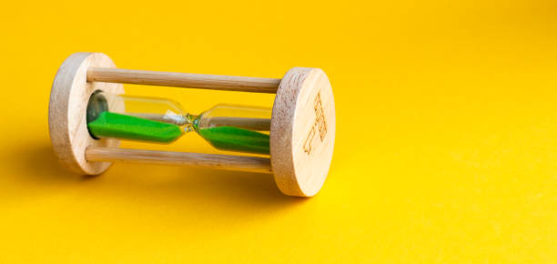 istock Hourglass with green sand inside on a yellow background 1222851048