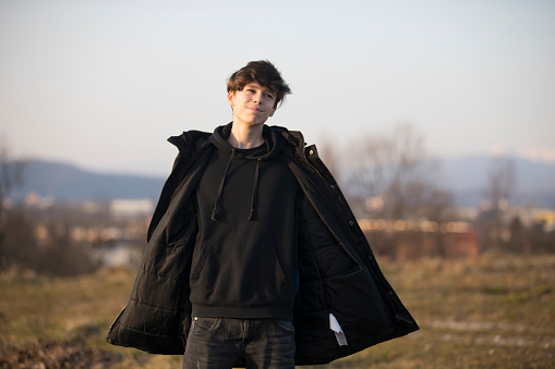 Portrait of Teenage Boy in Winter Jacket Standing in Rural Scene.