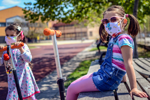 Sisters wearing pollution mask while driving trotinet Sisters wearing pollution mask while driving trotinet all weather running track stock pictures, royalty-free photos & images