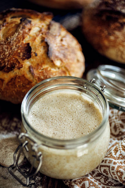 A jar with active rye sourdough for baking bread on a wooden table A jar with active rye sourdough for baking bread on a wooden table, close up yeast starter stock pictures, royalty-free photos & images