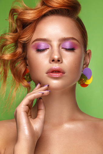 Beautiful girl with unusual accessories and make-up on a bright background. Beauty face. Photo taken in the studio