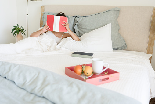 Mature hispanic woman reading in bed in the morning