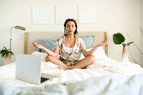 istock Mature hispanic woman learning to meditate on line while sitting in bed 1222857955