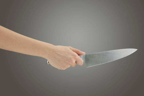 istock Kitchen knife in a woman hand isolated on a gray background 1222858700