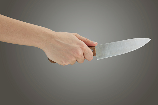 Kitchen knife in a woman hand isolated on a gray background