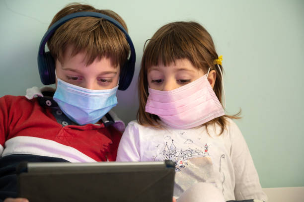 istock Brother and sister with masks at home 1222859615
