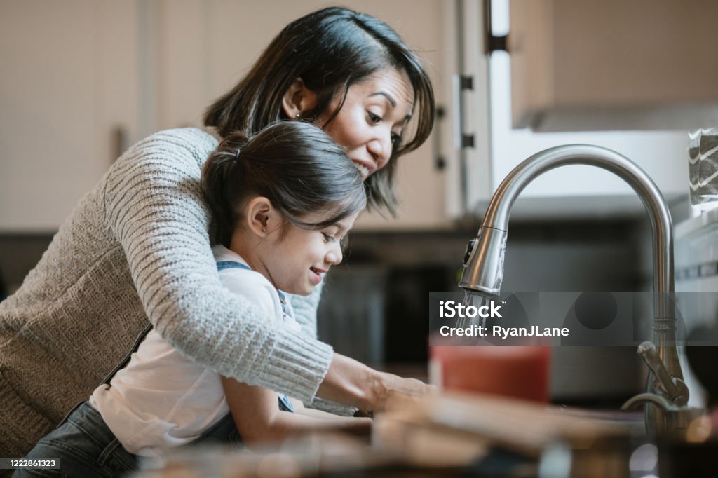 Mother Helps Daughter Wash Hands With Good Technique A mom teaches her little girl how to properly wash and disinfect her hands to keep them free of virus and bacteria germs.  Part of a regular routine, or the new normal with social distancing and working from home during the Covid-19 Pandemic. Washing Hands Stock Photo