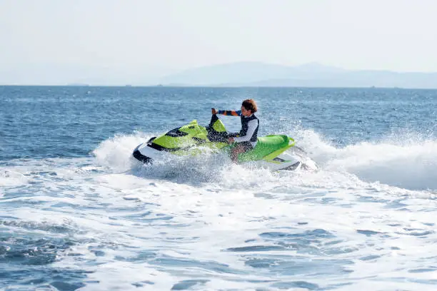 Man drives yellow jet ski on turquoise sea on a blue day