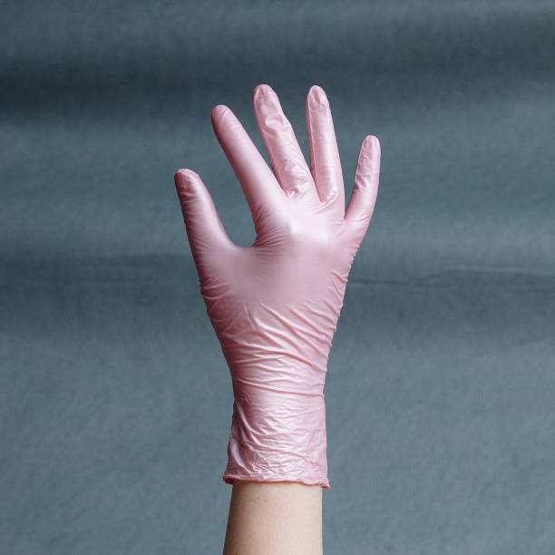 istock Hand in pink nitrile glove on a gray background with a gradient. 1222866207
