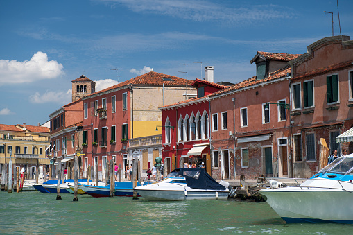 Murano, Italy - May 21, 2018. Canal view with tourists walking on streets in Murano. Murano is a series of islands in the Venetian  lagoon linked by bridges  in northern Italy. It is a tourist attraction famous for its glass-making industry.