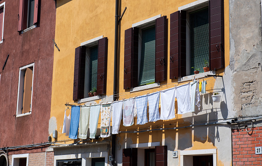 Murano, Italy - May 21, 2018. Houses with towels hanging out of windows in Murano. Murano is a series of islands in the Venetian  lagoon linked by bridges  in northern Italy. It is a tourist attraction famous for its glass-making industry.