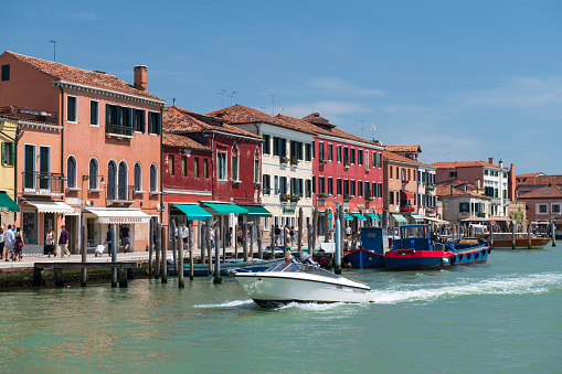 Murano, Italy - May 21, 2018. Canal view with tourists walking on streets in Murano. Murano is a series of islands in the Venetian  lagoon linked by bridges  in northern Italy. It is a tourist attraction famous for its glass-making industry.