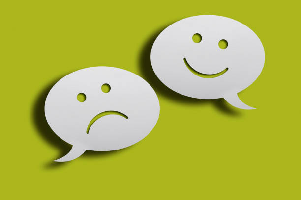 istock White chat bubbles with happy and sad face emoticon over green background. 1222867634