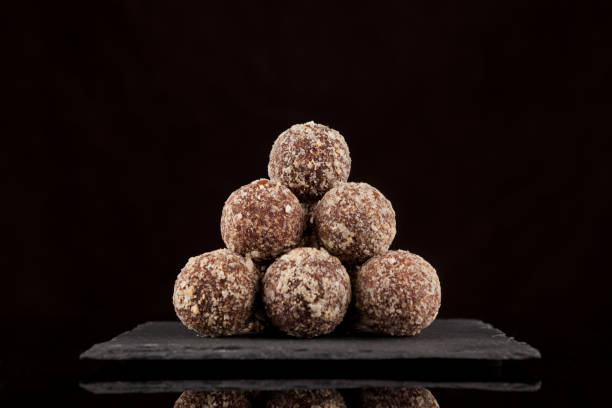 Bolas de energía. Los caramelos se apilan en forma de pirámide sobre un fondo oscuro, de cerca. Dulces sabrosos sin azúcar