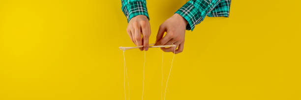 istock controling your mind, twisted sticks with ropes in the hand, puppet concept, isolated wide web banner 1222872524