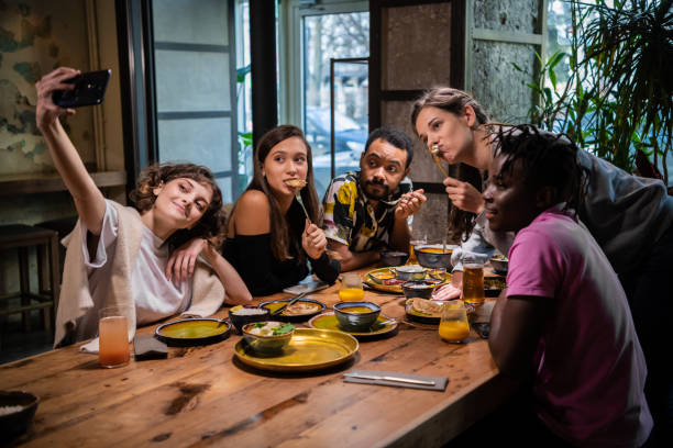 istock Five young friends sitting at the table in a cafe, taking selfie 1222872976