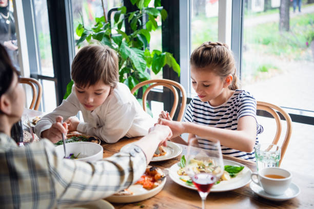 istock Two kids with their mother sharing food at dinner 1222873933