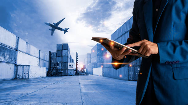 Global logistic or world of logistic concept. Businessman or manager using tablet standing with world map icon and shipping yard container and truck of transport background. fast or instant shipping. Global logistic or world of logistic concept. Businessman or manager using tablet standing with world map icon and shipping yard container and truck of transport background. fast or instant shipping. unloading photos stock pictures, royalty-free photos & images