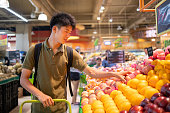 スーパーマーケットでリンゴを選ぶ10代の少年