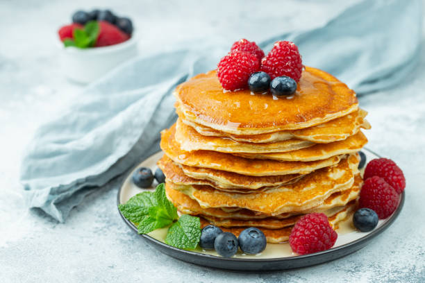 istock Close-up delicious pancakes, with fresh blueberries, raspberry's and honey on a light background 1222879848