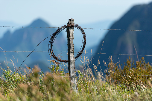 Image of a barbed wire fence and the landscape with the impressive mountain formation in the surroundings of the Serra do Corvo Branco at the Serra Catarinense in Urubici, Santa Catarina state - Brazil