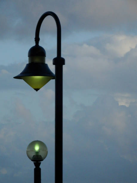 istock Two lampposts aligned against a cloudy blue sky 1222883816