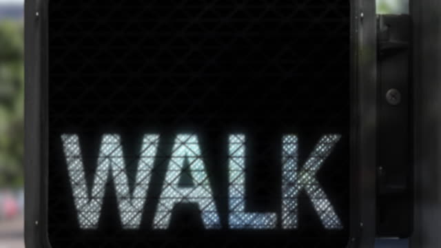 Closeup of Walk Signal showing the words WALK in white transitioning to a DON'T WALK warning