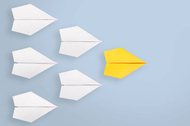 istock Leadership concepts with yellow paper airplane leading among white 1222889739