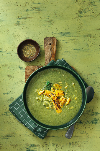 Summer Creamy Asparagus and Pea Soup with Corn and Chicken. Flat lay top-down composition on green background