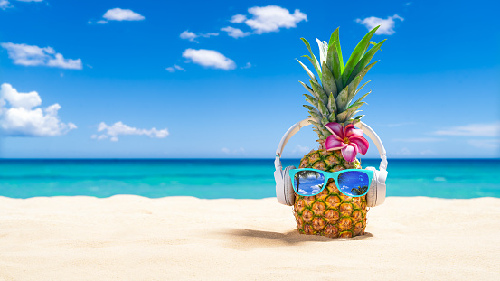 Pineapple with sunglasses, flip-flops and coconut drink on white sand beach in Vietnam