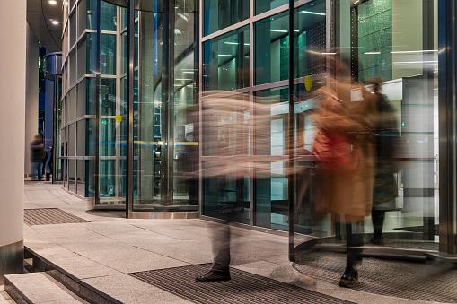 The flow of people passing through the rotating door of the modern office building