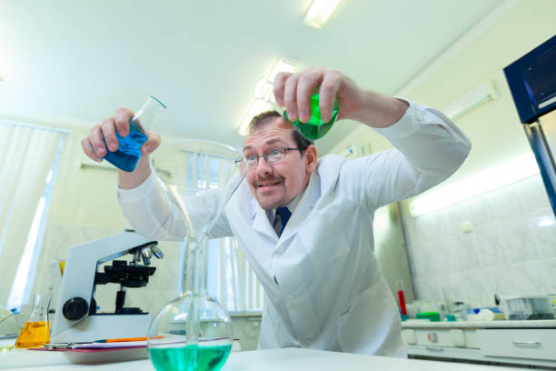 istock Chemist crazy. A mad scientist conducts experiments in a scientific laboratory. With a mad expression on his face, he mixes two liquids in a flask. COVID-19. COVID Coronavirus 1222903172