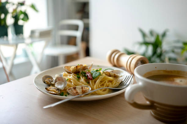 Seafood spaghetti with clams, prawns and cuttlefish in white plate on wooden table.