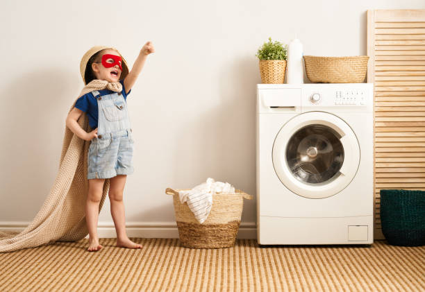 family doing laundry Beautiful child girl little helper is having fun and playing while doing laundry at home. washing machine photos stock pictures, royalty-free photos & images