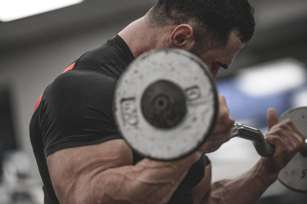istock strong young male in black jersey training biceps muscle with small iron barbell during fitness workout in sport gym 1222908925