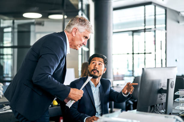 istock Businessman assisting colleague over computer 1222911495